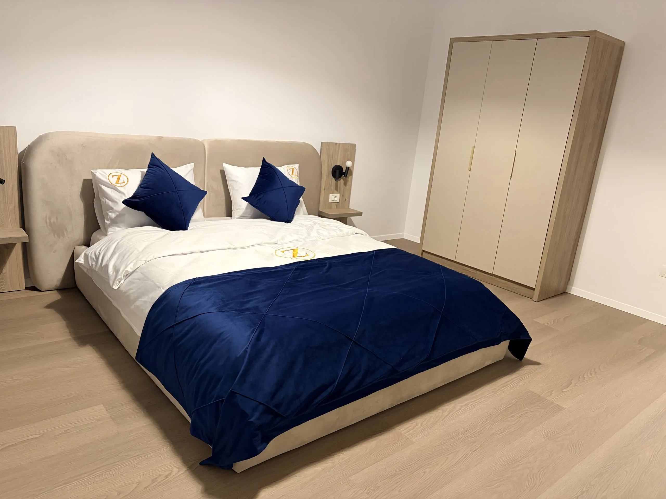 Bedroom with a navy duvet, upholstered headboard and a full-height wardrobe