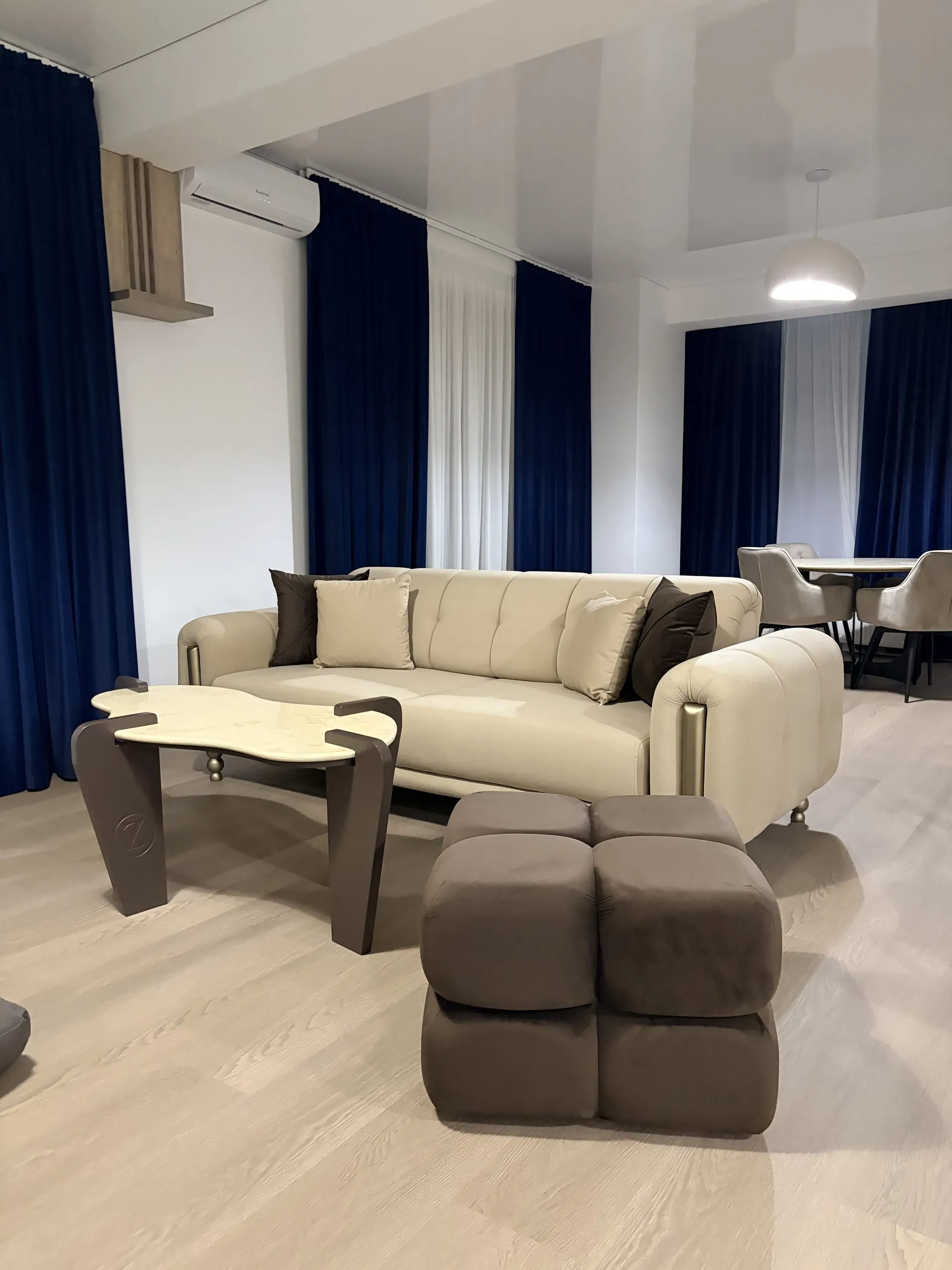 Living and dining areas together, framed by navy and sheer curtains