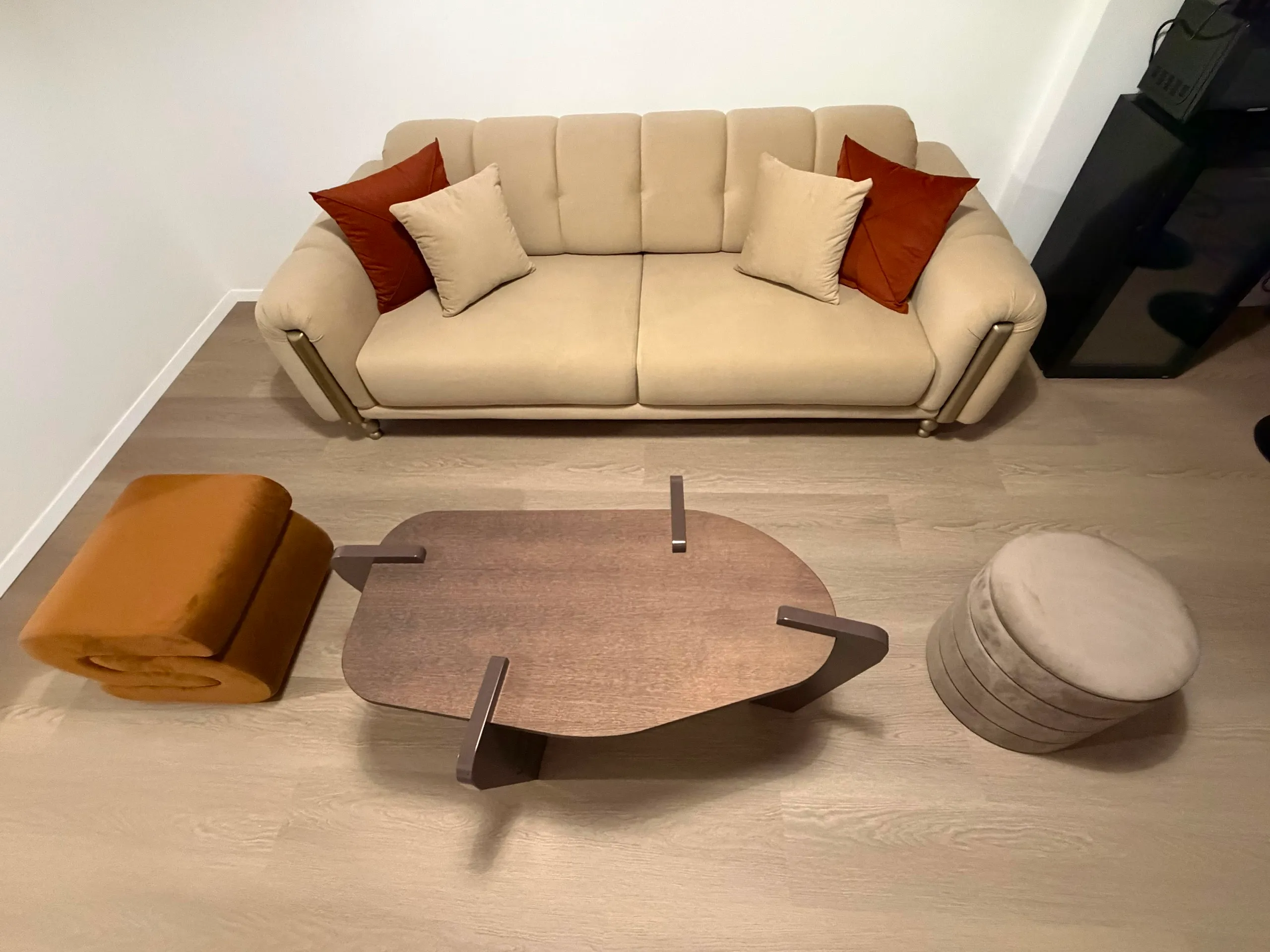 Living area with a comfortable sofa, sculptural coffee table and velvet poufs