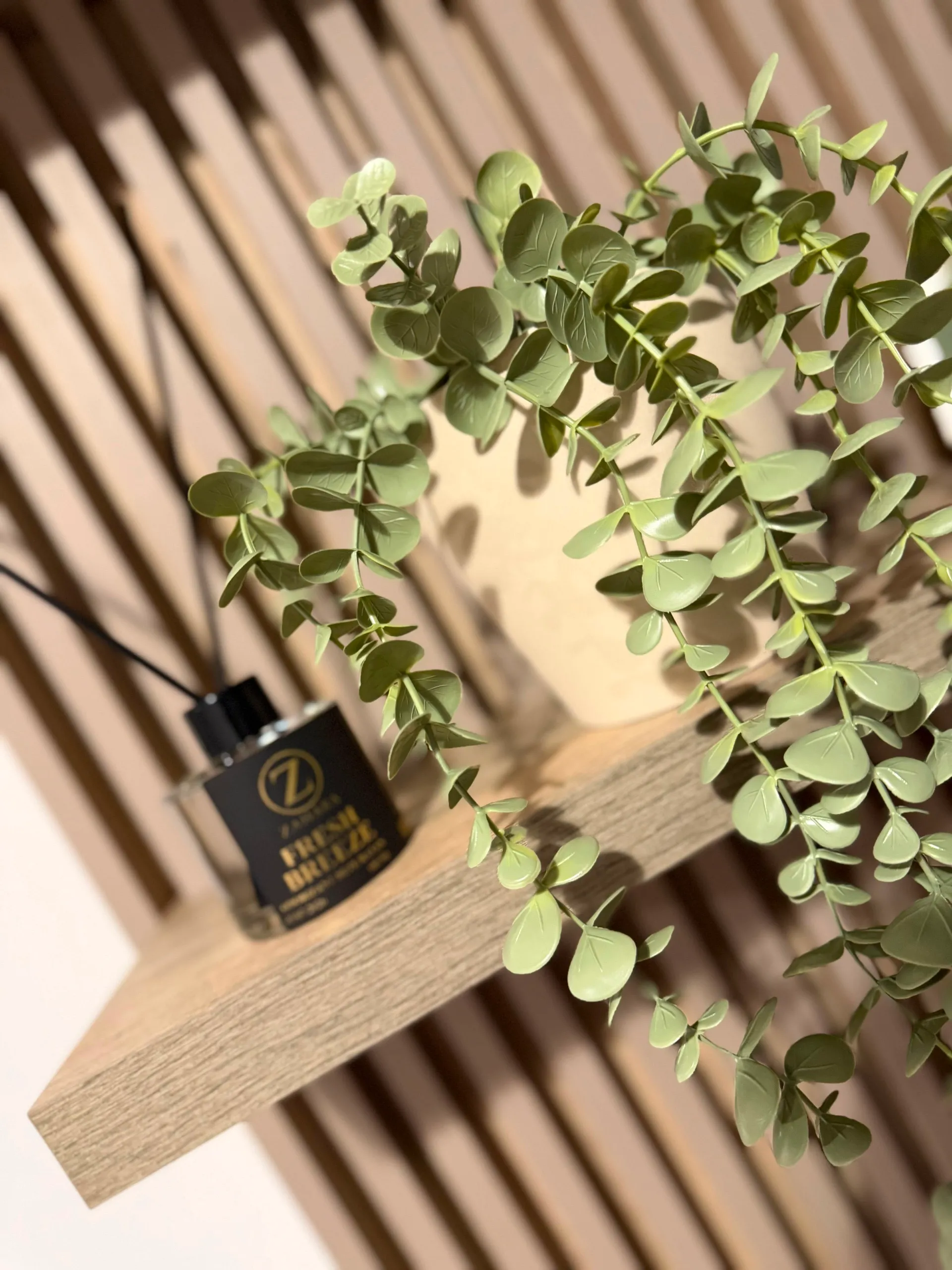 Zahara 'Fresh Breeze' scent diffuser and eucalyptus on a wood-slat shelf