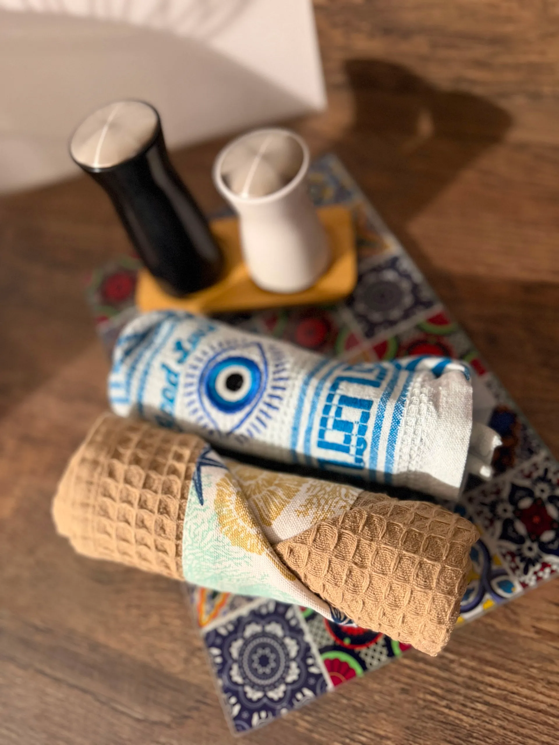 Rolled towels finished with a woven evil-eye pattern band